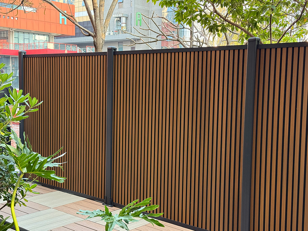 Fencly Dual Tone Slat Wall — premium WPC composite fence panel in Teak and Black, installed vertically along an Australian garden boundary.