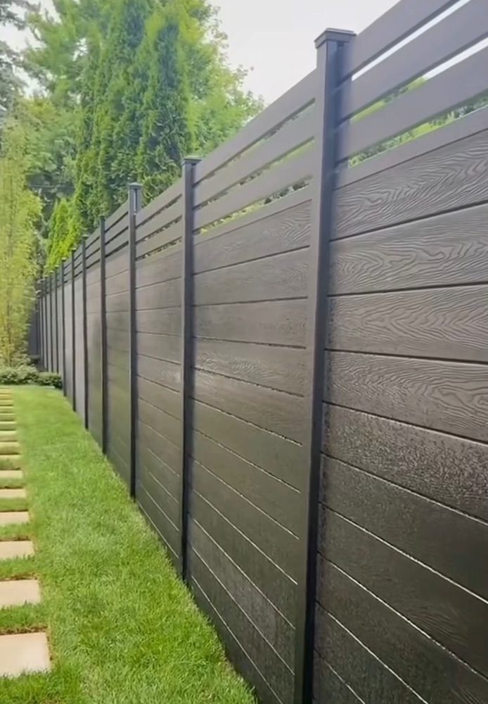 Fencly Privacy Fence: close-up of the co-extruded WPC board surface showing realistic wood-grain texture in charcoal.