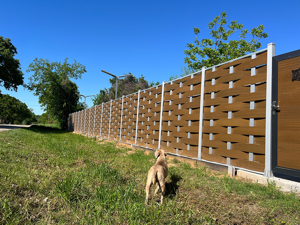 Fencly Woven Fence — hand-crafted basket-weave WPC composite boards following a curved boundary line.
